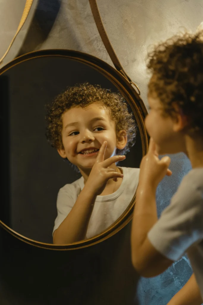 kid making silly faces in front of mirror